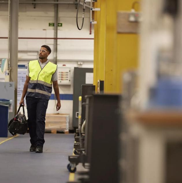 Un agent de sécurité portant un gilet jaune et transportant une boîte à outils dans un sous-sol