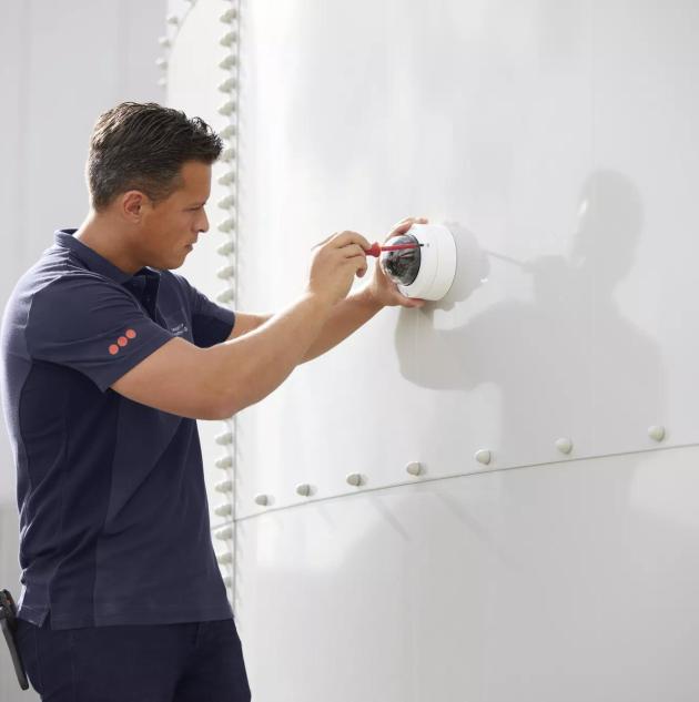 Un installateur monte une caméra de surveillance sur un mur